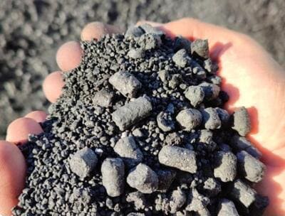 Mano sosteniendo biochar granulado